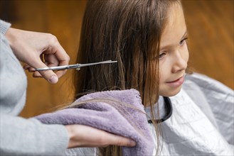 Hairdresser cutting little girl s hair