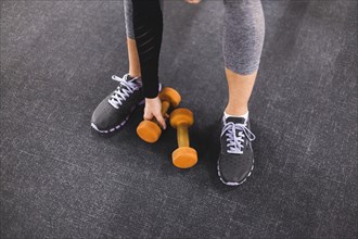 Low section view woman picking dumbbell gym