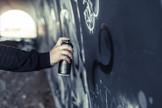 Close up person s hand spraying paint with aerosol can graffiti wall