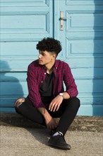 Sitting ethnic teenager checkered shirt curb