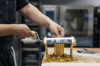 Male chef using machine chop fresh pasta dough