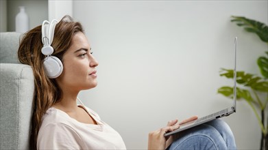 Side view woman with headphones using laptop