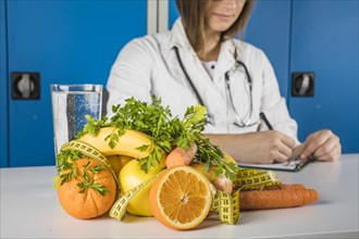 Fresh fruits with measuring tape front female dietician writing clipboard