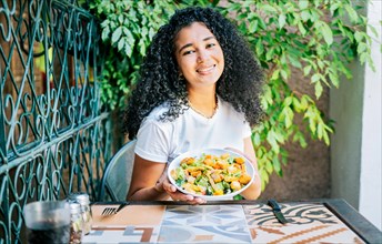 Beautiful girl sitting holding a caesar salad. Portrait of smiling girl eating caesar salad. Concept of healthy food and healthy life