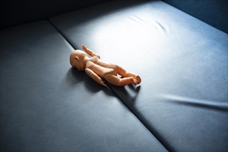 A doll lies on a blue base