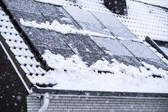Solar panels covered with snow on the roof of a house in Essen