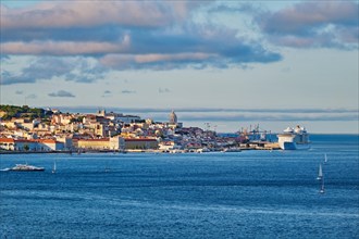 View of Lisbon over Tagus river from Almada with yachts tourist boats and passenger ferry and moored cruise liner on sunset with dramatic sky. Lisbon