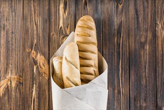 Baguettes wrapped paper wooden background