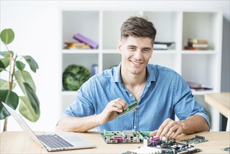 Smiling young male it technician with hardware equipment s