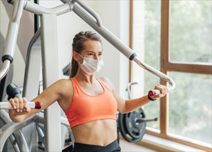 Woman gym doing exercises with medical mask