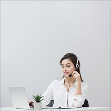 Front view woman working desk while wearing headset looking laptop