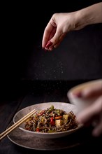 Hand sprinkling salt bowl noodles with vegetables