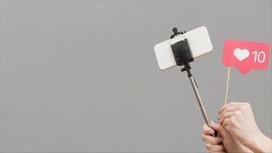 Close up blogger holding selfie stick with mobile phone