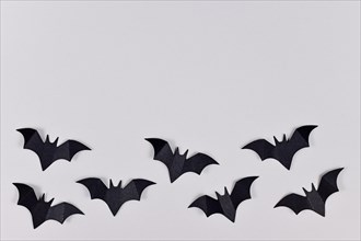 Black papercraft flying Halloween bats at bottom of gray background with empty copy space