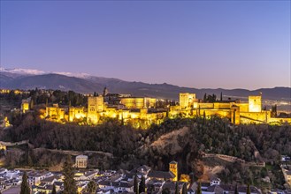 View from the Mirador de San Nicolas of Alhambra and the snow-capped mountains of the Sierra Nevada at dusk