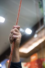 A person holding a rope for belaying in a climbing gym