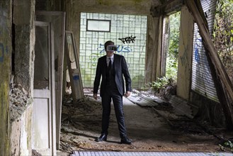 Man dressed in suit wearing VR glasses in a dilapidated office building