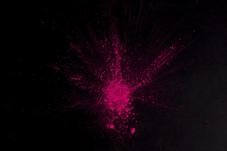 Overhead view pink color exploding black surface