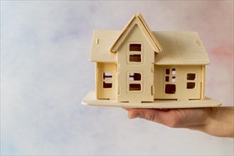 Close up hand holding house model against textured background