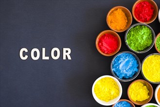 Color text with different types holi color powder bowl black background