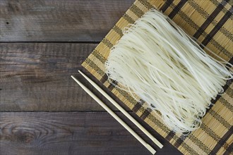 Raw rice noodles place mat chopsticks weathered table