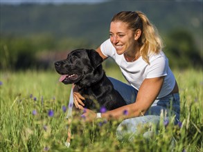 Portrait of a woman and a Labrador dog on a meadow