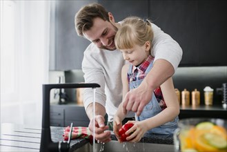 Girl helping father wash vegetables