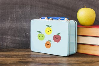 Lunchbox near stack books apple