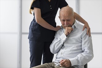 Nurse consoling old crying man