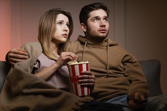 Couple watching tv eating popcorn