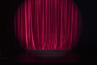 Empty stage with light spot on red curtain