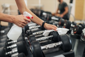 Woman gym disinfecting weights before using them