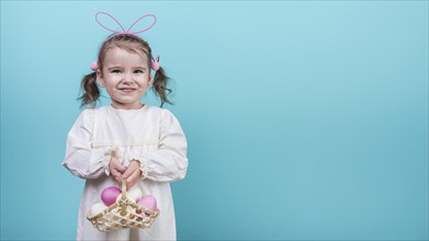 Little girl bunny ears holding basket with easter eggs