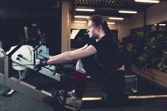 Woman exercising rowing machine gym