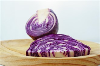 Sliced purple cabbage on a wooden board with white background