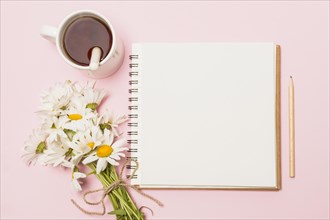 Notebook near flowers cup drink