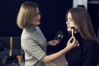 Side view makeup artist applying powder model