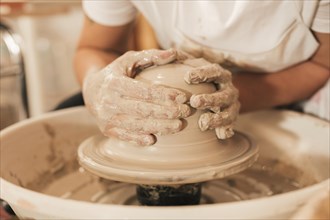 Craftswoman creating pottery working wheel shaping clay