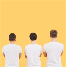 Rear view men white t shirt standing against yellow background