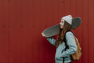 Beautiful female skater holding her skateboard