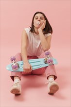 Girl chewing gum holding skateboard