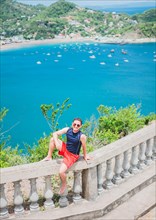 Portrait of tourist man in the view of the bay of San Juan del Sur. Happy tourist sitting in a viewpoint of a bay