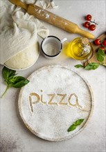 Top view pizza dough with tomatoes word written flour