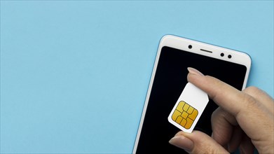 Top view hand holding sim card with smartphone copy space