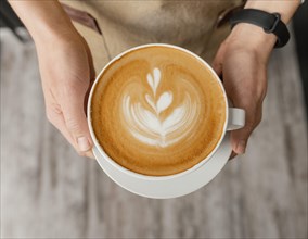 Top view female barista holding decorated cup coffee hands