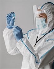 Doctor holding vaccine bottle while wearing protective equipment