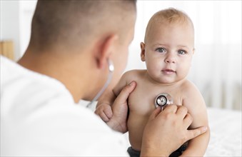 Back view doctor listening little baby with stethoscope