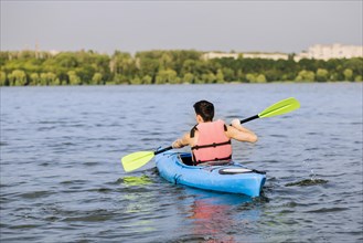 Rear view man using paddle kayaking
