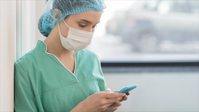 Side view nurse with mask checking mobile