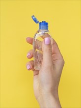 Front view hand holding plastic bottle with hand sanitizer